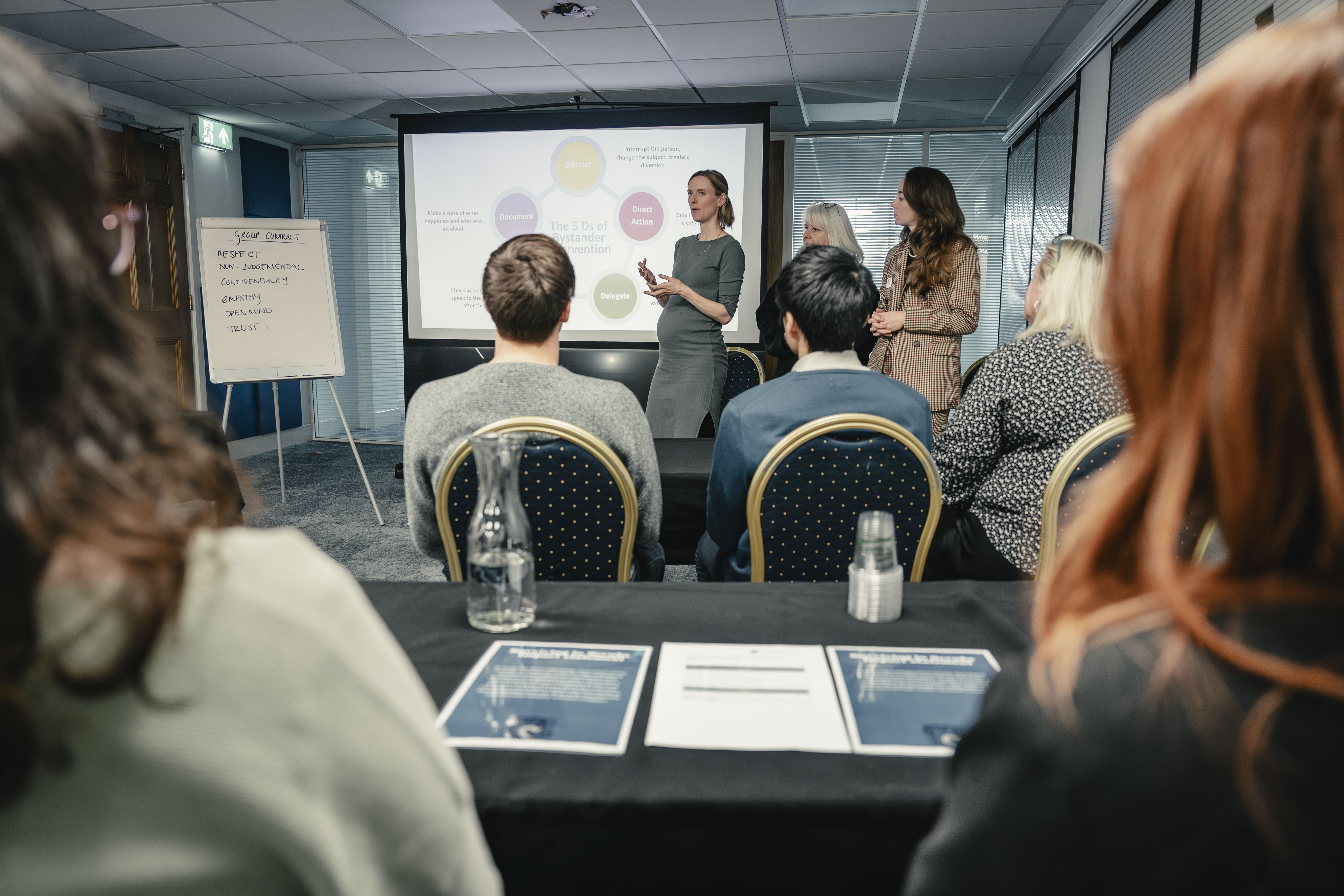 Training session with delegates sitting listening to three presenters